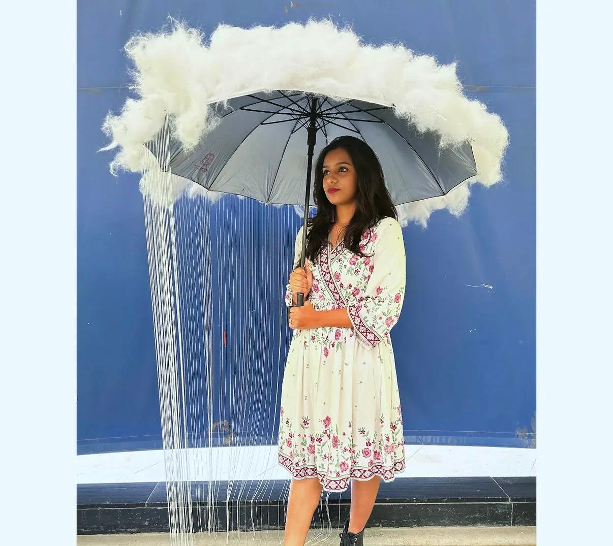 Sahuuu standing beneath a cloud shaped umbrella installation